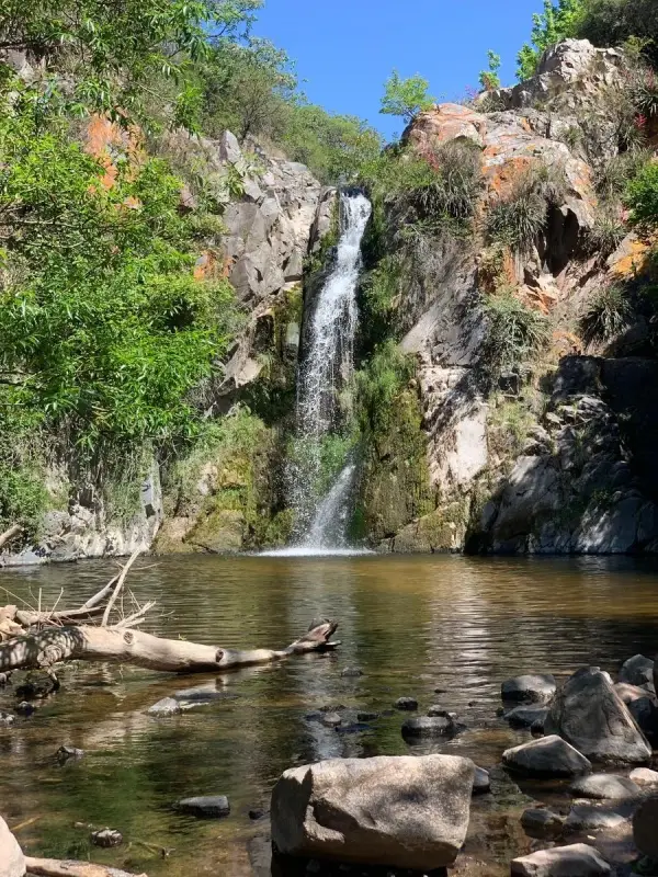 La cascada cayendo entre rocas y vegetación sobre una olla de agua cristalina, en la Reserva Hídrica y Natural Municipal Salsipuedes