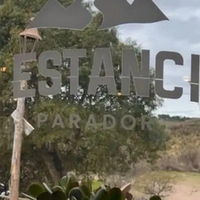 El cartel de La Estancita Parador con el monte de fondo